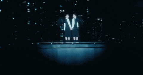 two women are standing next to each other in the dark .