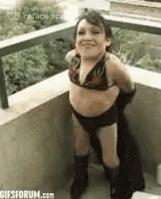 a little girl is standing on a balcony wearing a bikini and boots .