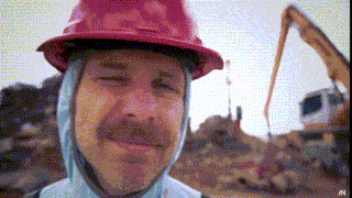 a man wearing a red hard hat and a blue hooded jacket with the letter n on the bottom right