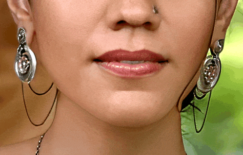 a close up of a woman 's face with earrings and a nose ring