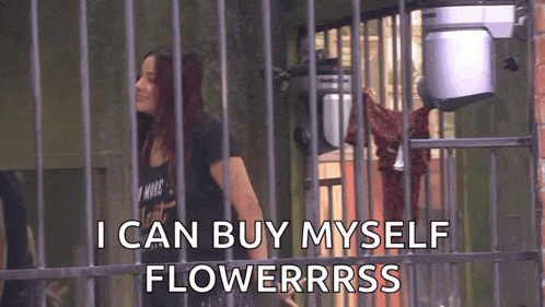 a woman is standing in front of a fence with the words `` i can buy myself flowerrrss '' .