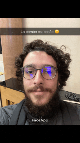 a man with glasses and a beard has a face app sticker on his neck