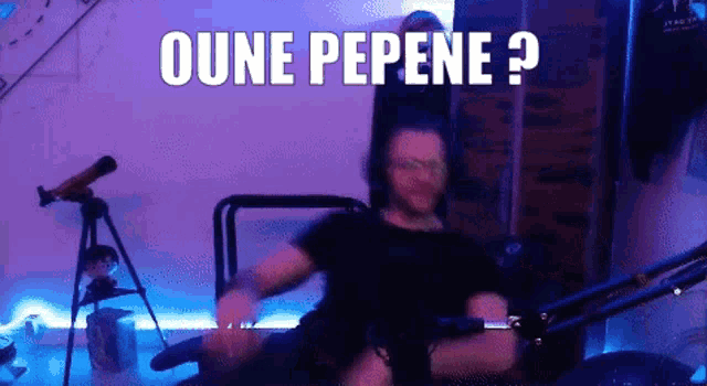 a man is sitting in front of a microphone with the words oune pepene written on the screen behind him