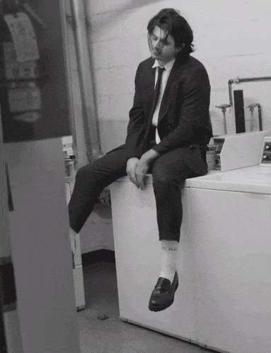 a man in a suit and tie is sitting on a washing machine