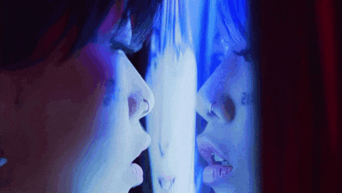 a woman with a nose ring is looking at herself in the mirror