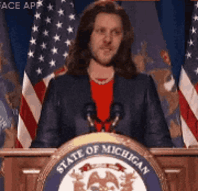 a man stands at a podium with the state of michigan logo on it