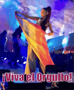 a woman dancing with a flag and the words " viva el orgullo " behind her