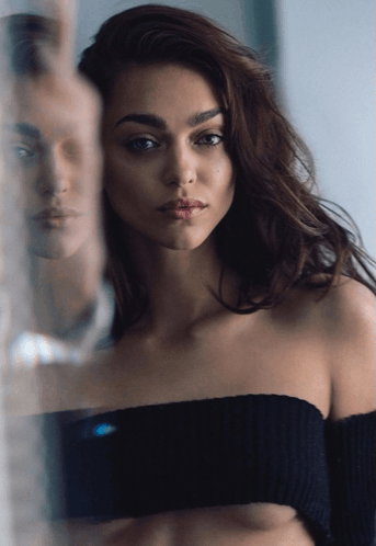 a woman in a black off the shoulder top is standing in front of a mirror