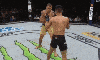 two men are fighting in a boxing ring with a monster logo on the ground .