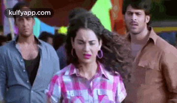 a woman in a plaid shirt is standing in a crowd of people .