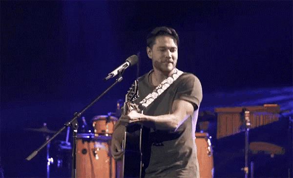a man singing into a microphone while playing an acoustic guitar