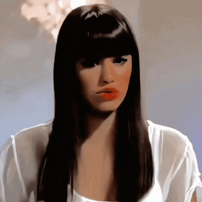 a woman with long black hair and red lips is wearing a white top