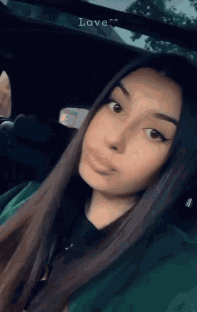 a woman is taking a selfie in the back seat of a car with the word love above her head