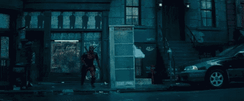 a man in a deadpool costume is running down a city street .