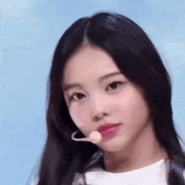 a close up of a girl wearing a microphone and a white shirt .