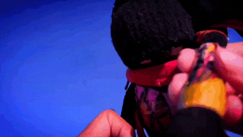 a close up of a person holding a bottle with a blue background