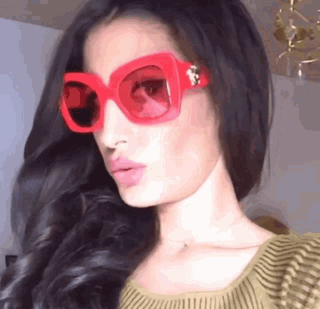 a woman wearing a green sweater and red sunglasses .
