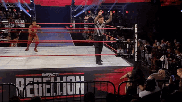 a female wrestler stands in a wrestling ring that says impact