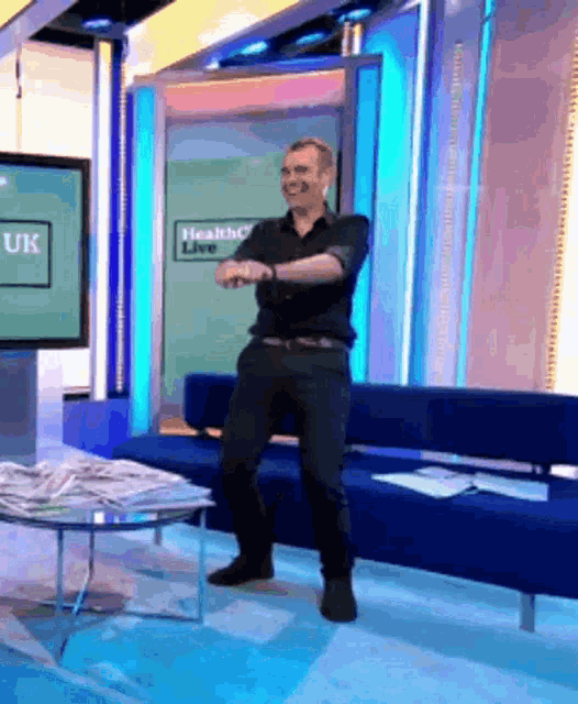 a man is dancing in front of a tv screen that says health live