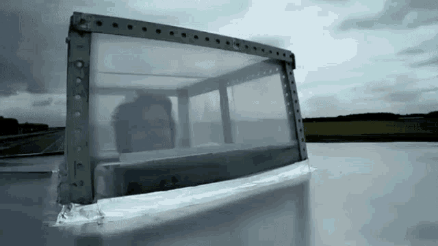 a man is looking out of a clear window with the bbc logo on the bottom right