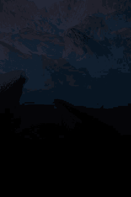 a dark landscape with mountains in the background at night