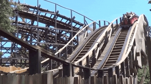 a roller coaster is going down a hill with a fence in the background