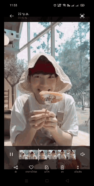 a phone screen shows a person eating a sandwich with a fork