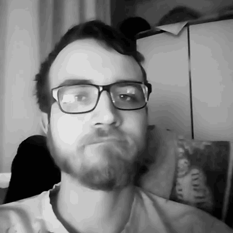 a man with glasses and a beard is making a face in a black and white photo