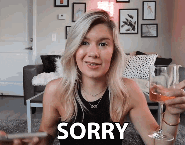 a woman is holding a glass of wine and says " sorry "