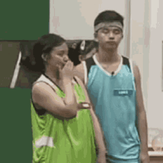 a man and a woman are standing next to each other in a room . the man is wearing a headband .