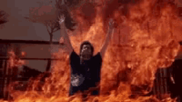 a man is laying on top of a burning building with his arms outstretched .