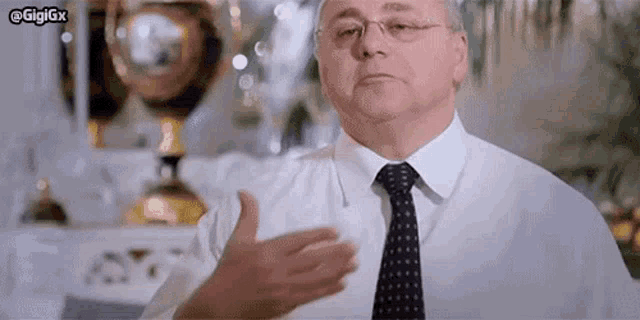 a man in a white shirt and tie is giving a thumbs up sign .