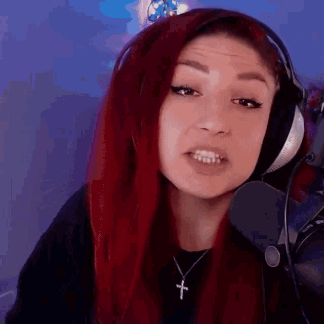 a woman with red hair wearing headphones and a necklace with a cross