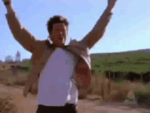 a man is standing with his arms in the air in a field .