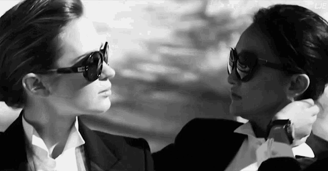 two women wearing sunglasses are looking at each other in a black and white photo that says lje