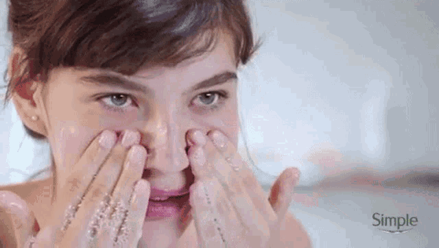 a woman is cleaning her face with soap and water .