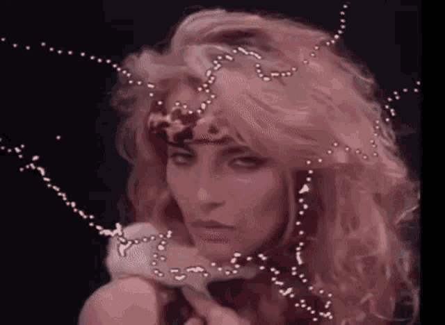 a woman with blonde hair and a leopard print headband is holding a snake in her hand .