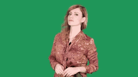 a woman in a floral shirt is standing on a green screen .