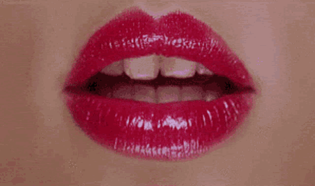 a close up of a woman 's red lips with white teeth