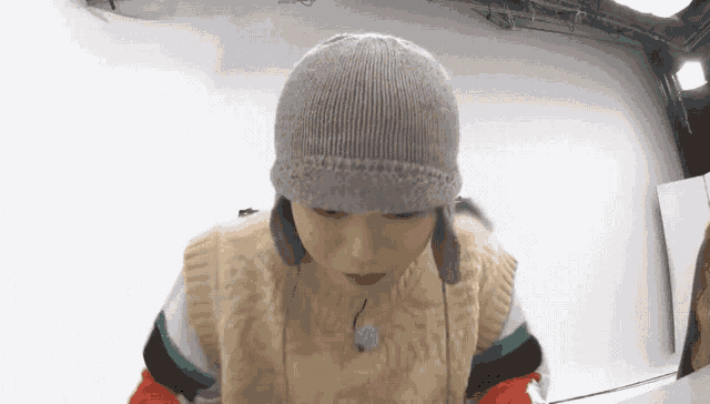 a person wearing a sweater vest and a knitted hat with ear flaps