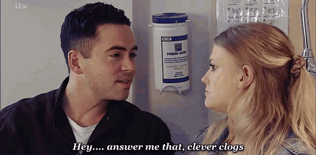 a man and a woman are looking at each other in front of a container that says premi wipes