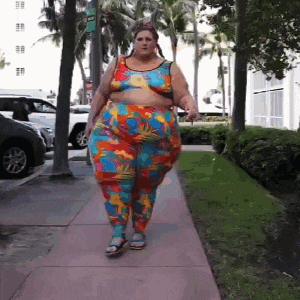 a woman wearing a colorful outfit is walking down a sidewalk