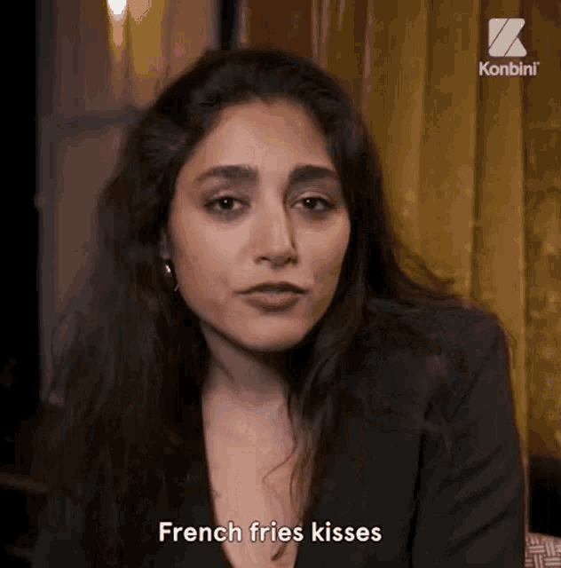 a woman is talking about french fries kisses while wearing a black jacket .
