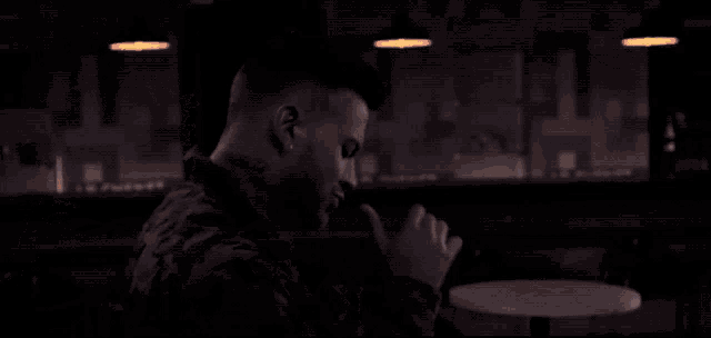 a man sits at a table with his hands folded in front of him