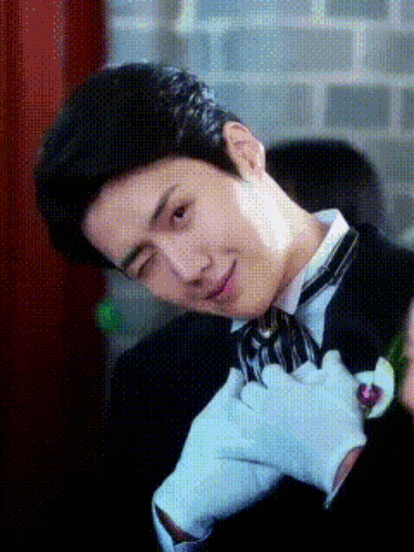 a man wearing a tuxedo and white gloves is making a face