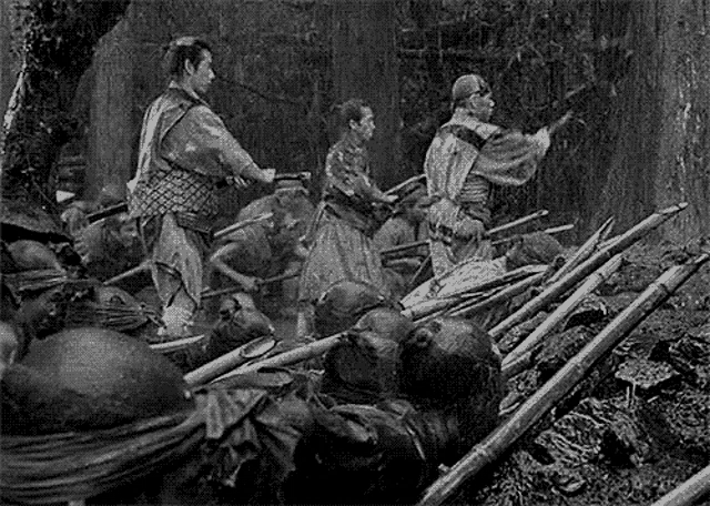 a black and white photo of a group of samurai fighting in the woods .