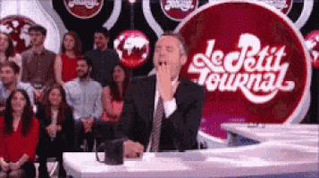 a man in a suit and tie is yawning in front of a sign that says le petit journal