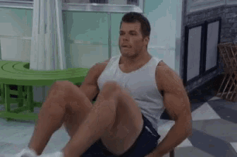 a man in a tank top and shorts is doing exercises on a bench .
