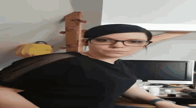 a woman wearing glasses is standing in front of a television in a living room .