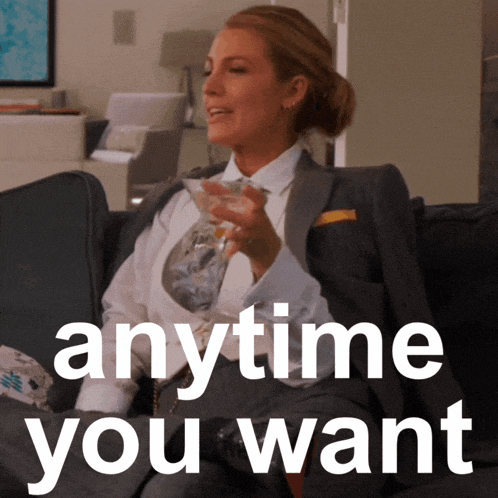 a woman in a suit sits on a couch holding a martini and the words anytime you want behind her